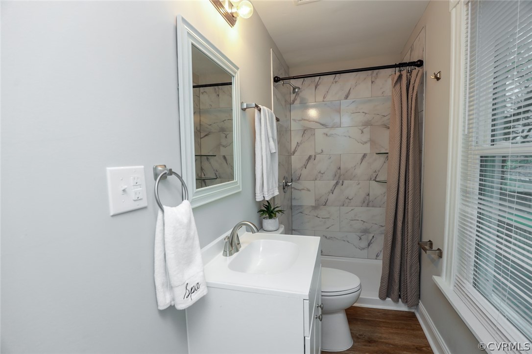 Full bathroom with toilet, vanity, shower / bathtub combination with curtain, and wood-type flooring