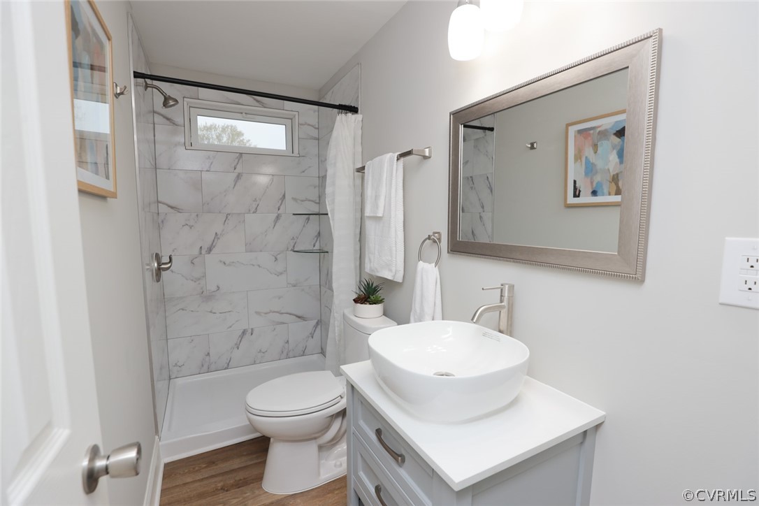 Full bathroom featuring toilet, oversized vanity, hardwood / wood-style flooring, and shower / bathtub combination with curtain