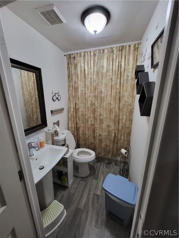 Bathroom with toilet, hardwood / wood-style flooring, and sink