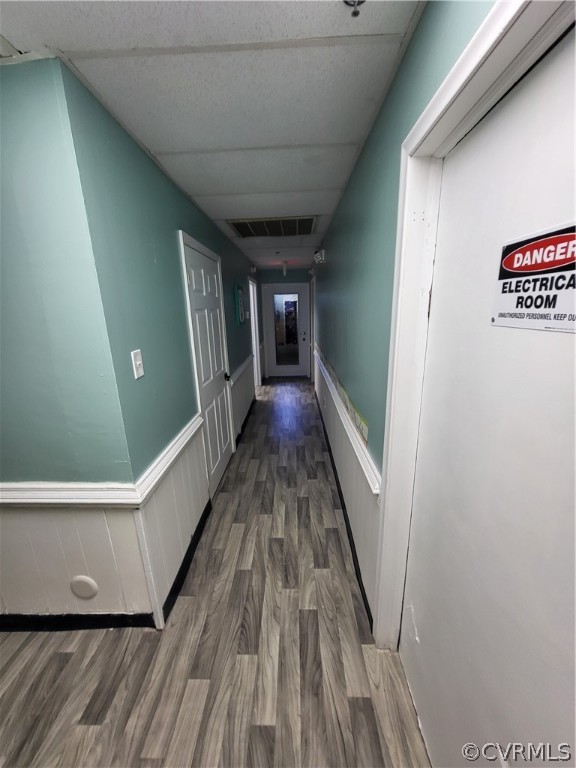 Hallway featuring dark wood-type flooring and a paneled ceiling