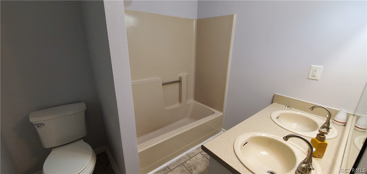 Full bathroom with double vanity, tile floors, toilet, and shower / bath combination
