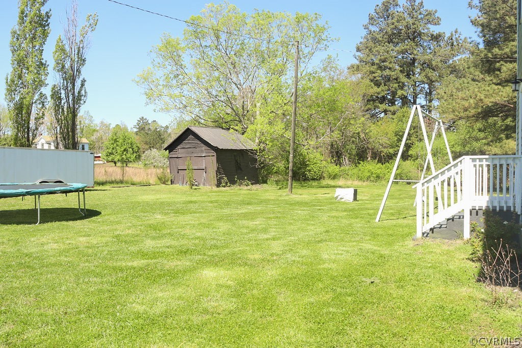 View of yard featuring a trampoline and a storage unit