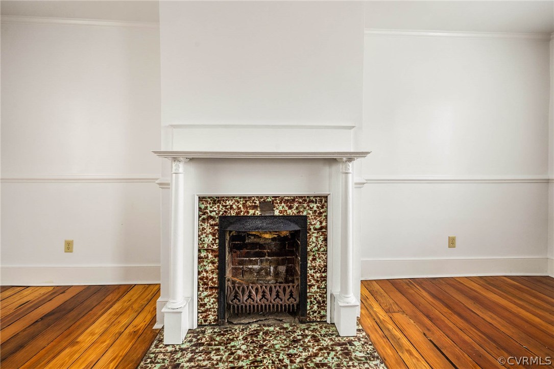 Room details featuring ornamental molding, dark wood-type flooring, and a fireplace