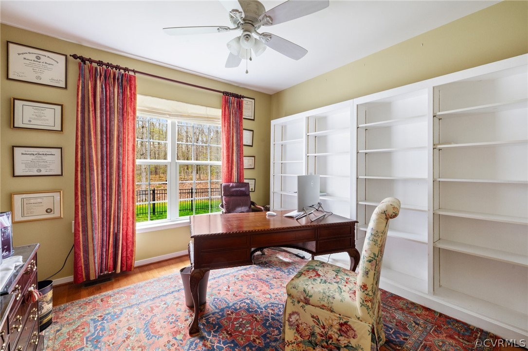 Office with ceiling fan and wood flooring, bookcases