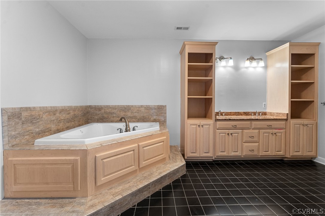 Bathroom featuring a tub, dual vanity, and tile flooring