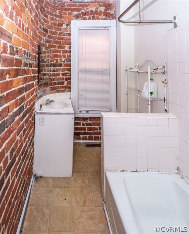 Bathroom with vanity, tile flooring, and brick wall