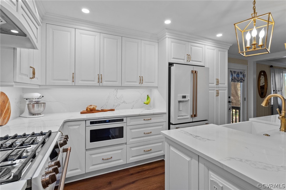 Kitchen with white cabinets, high quality appliances, premium range hood, and light stone​​‌​​​​‌​​‌‌​‌‌​​​‌‌​‌​‌​‌​​​‌​​ counters