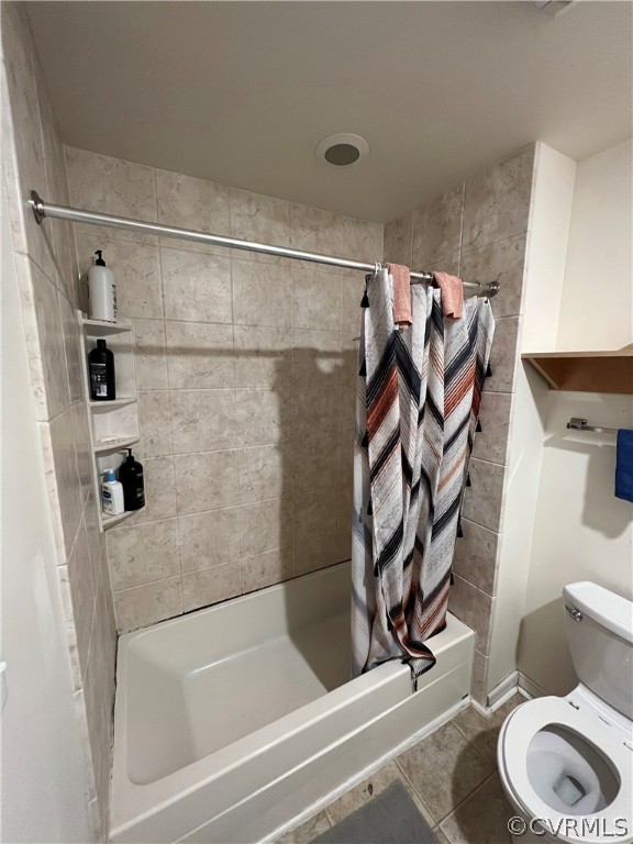 Bathroom with toilet, shower / tub combo, and tile floors