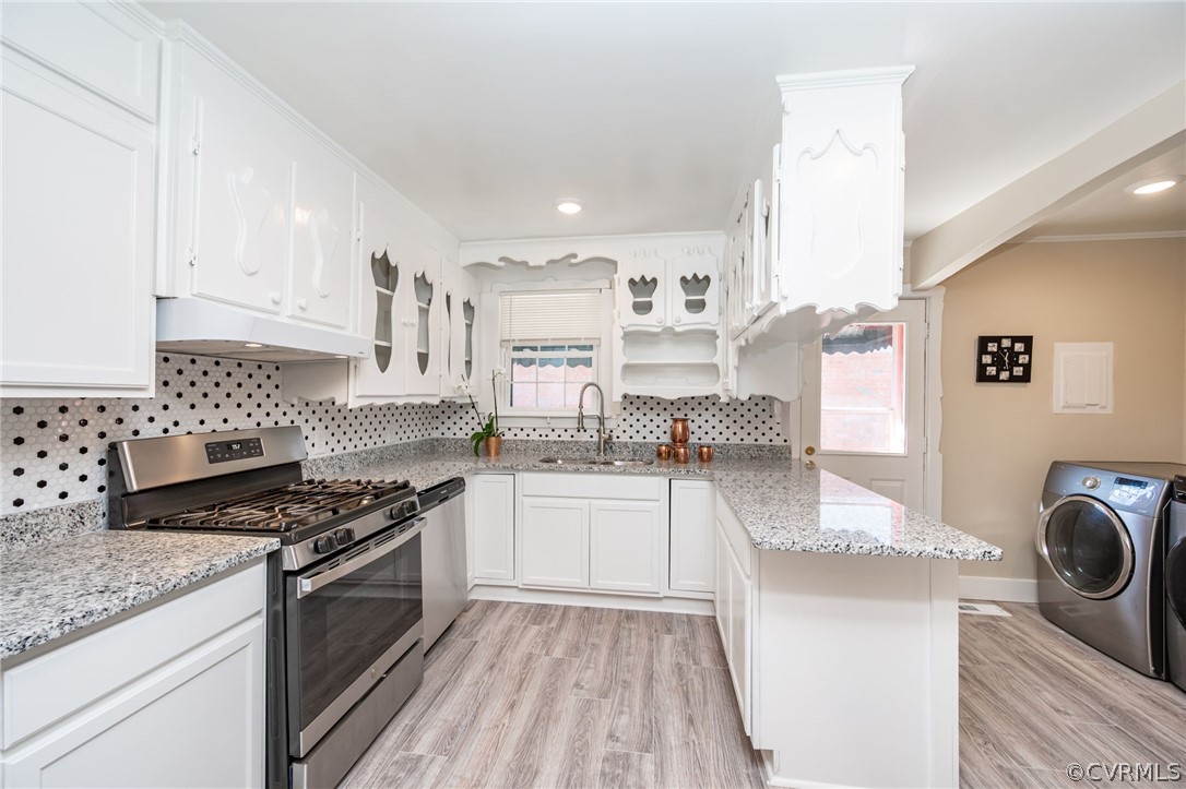 Kitchen featuring a healthy amount of sunlight, white cabinetry, stainless steel range with gas stovetop, and sink