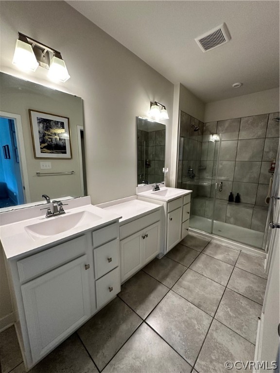 En-suite Bathroom featuring a shower with door, double vanity, and tile floors