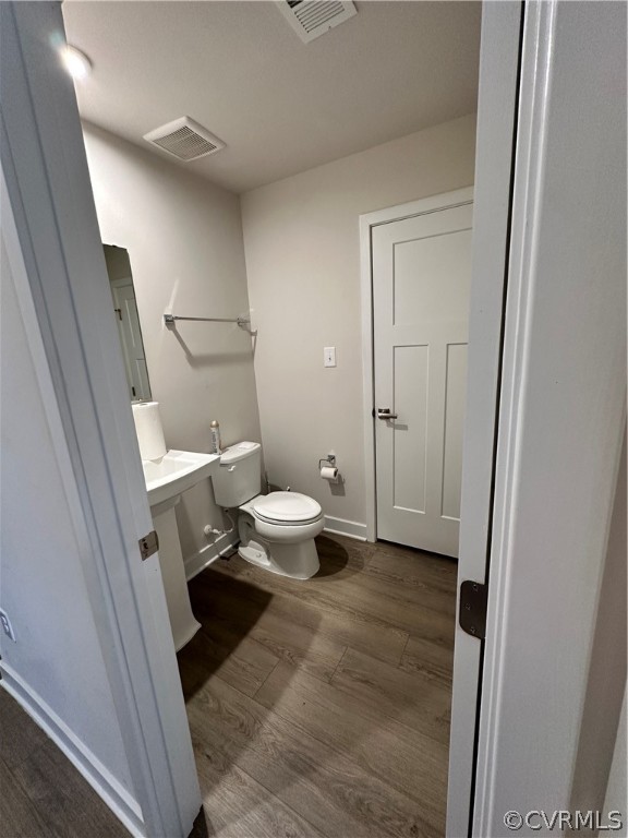 1st level 1/2 Bathroom featuring toilet and hardwood / wood-style floors