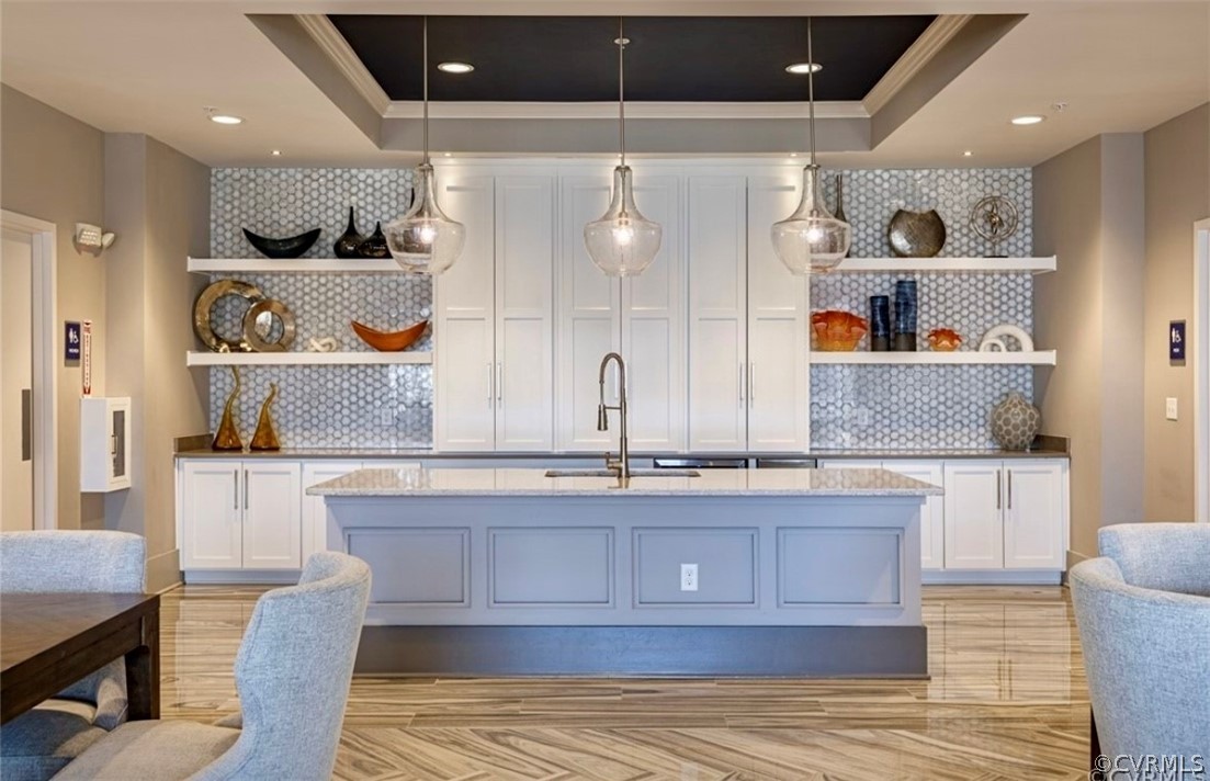 Bar featuring white cabinets, backsplash, and a raised ceiling