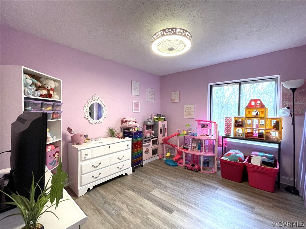 Playroom with a textured ceiling and light wood-type flooring