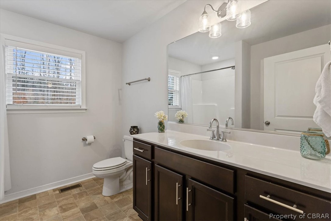 Bathroom featuring toilet, tile flooring, vanity, and an inviting chandelier