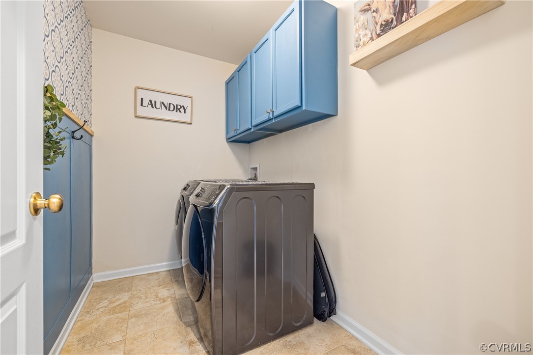 Clothes washing area featuring light tile floors, cabinets, and separate washer and dryer