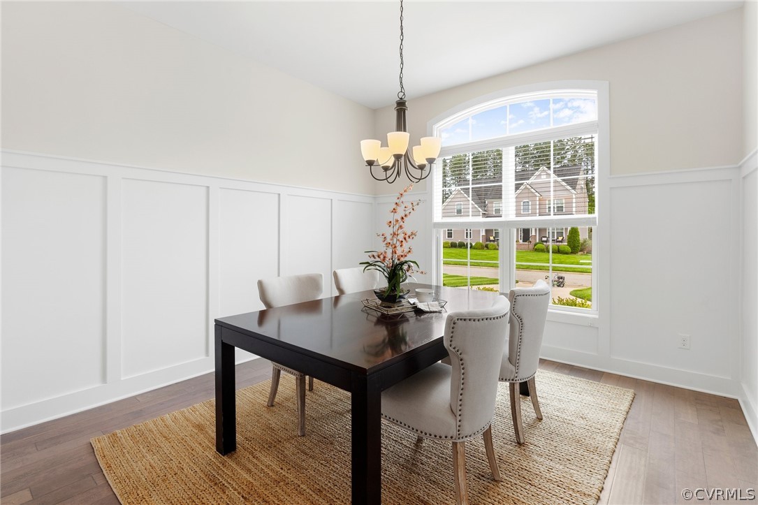 Separate Formal Dining Room features wainscot trim wall, hardwood flooring, large windows and a column