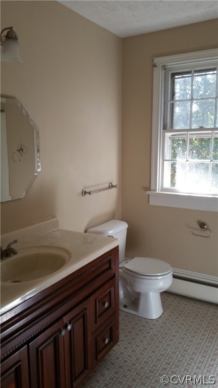 Bathroom featuring toilet, a baseboard heating unit, a textured ceiling, vanity, and tile flooring