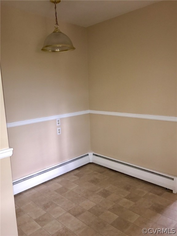 Tiled spare room featuring a baseboard heating unit