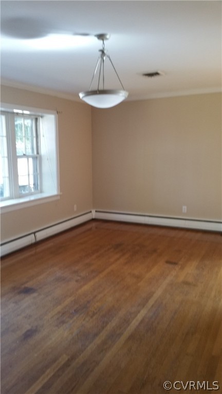 Empty room featuring hardwood / wood-style floors and a baseboard radiator