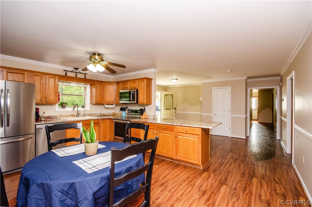 Kitchen featuring ceiling fan, hardwood / wood-style floors, stainless steel appliances, and ornamental molding