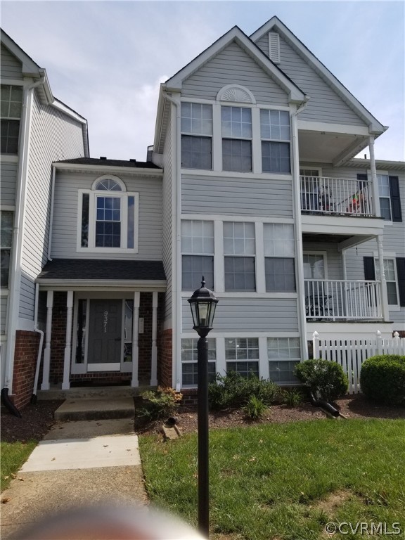 Townhome / multi-family property with a balcony and a front yard