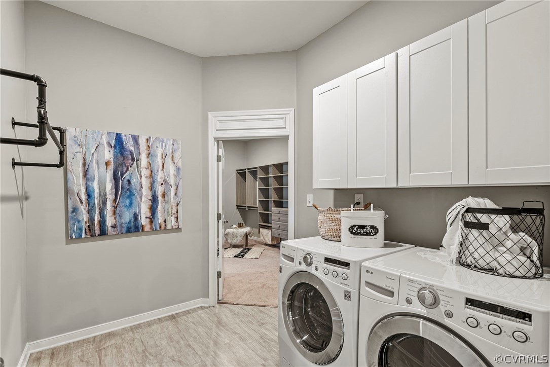 Laundry area featuring independent washer and dryer, light hardwood / wood-style flooring, and cabinets