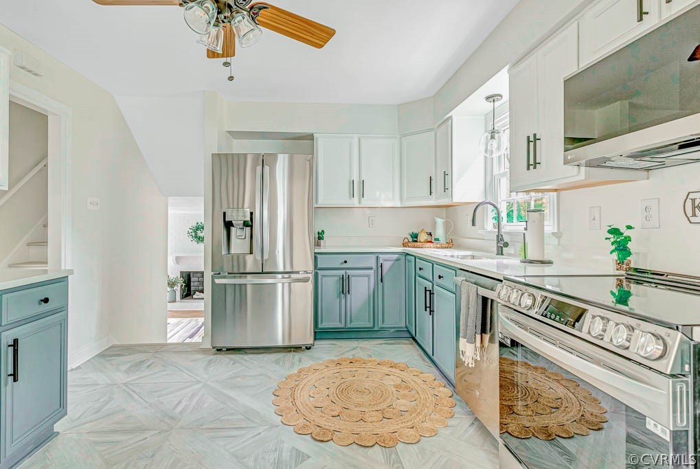 Kitchen featuring appliances with stainless steel finishes, ceiling fan, sink, white cabinetry, and blue cabinets