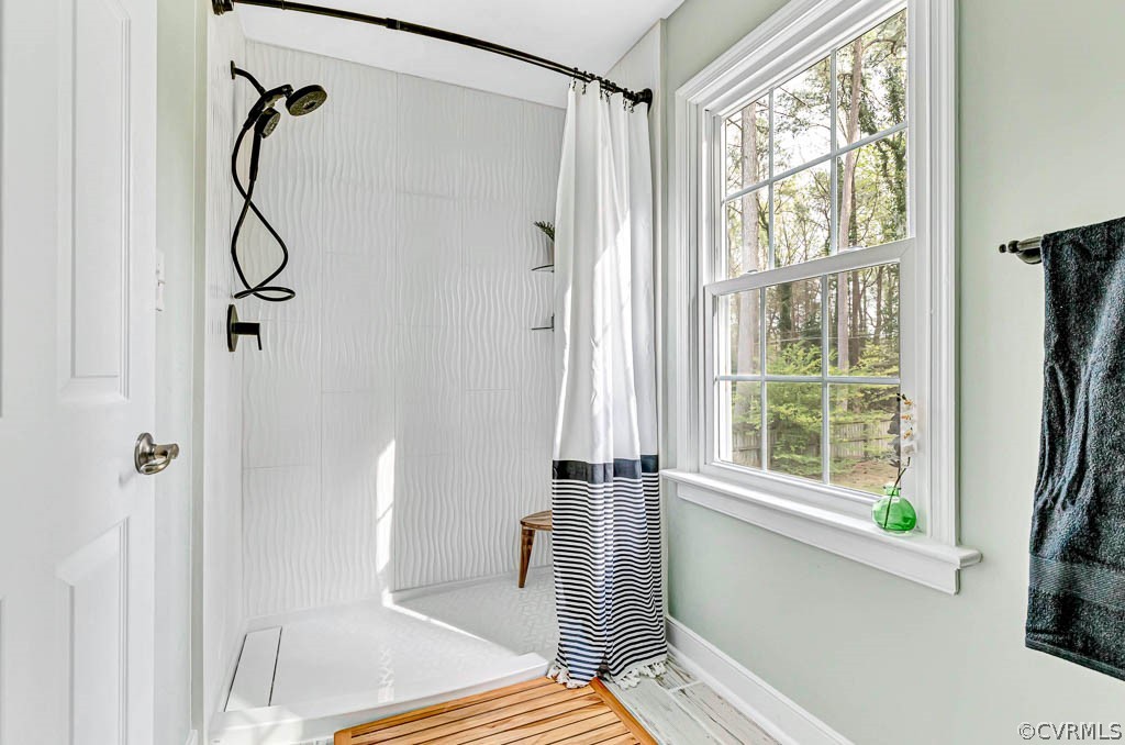 Bathroom featuring curtained shower, a wealth of natural light, and hardwood / wood-style flooring