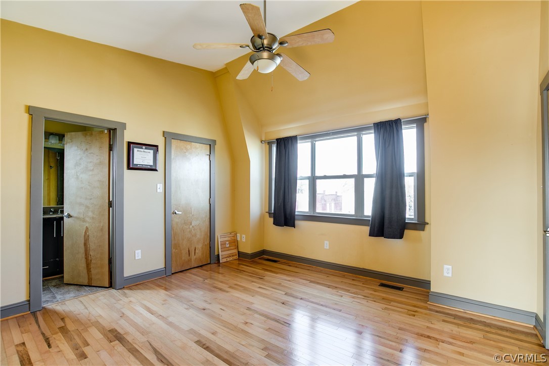 Unfurnished bedroom with ceiling fan, connected bathroom, and light hardwood / wood-style flooring