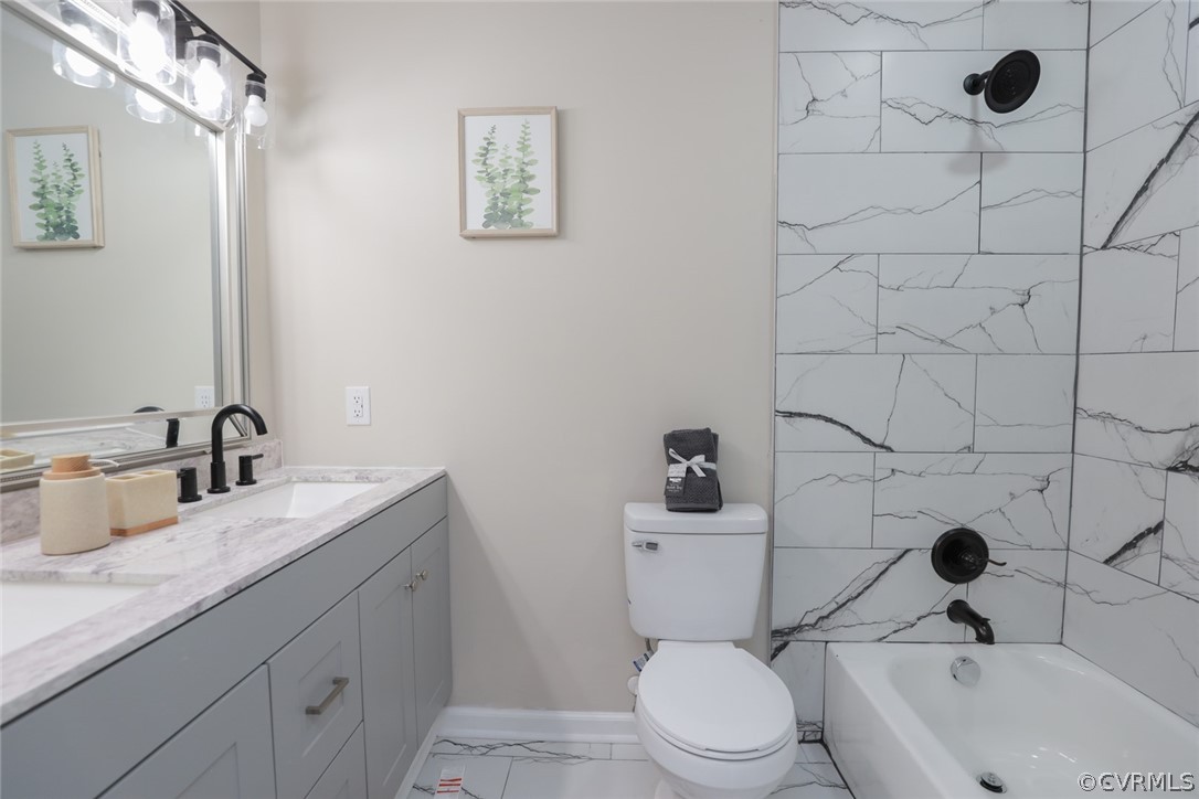 Full bathroom with toilet, tiled shower / bath, tile floors, dual sinks, and large vanity