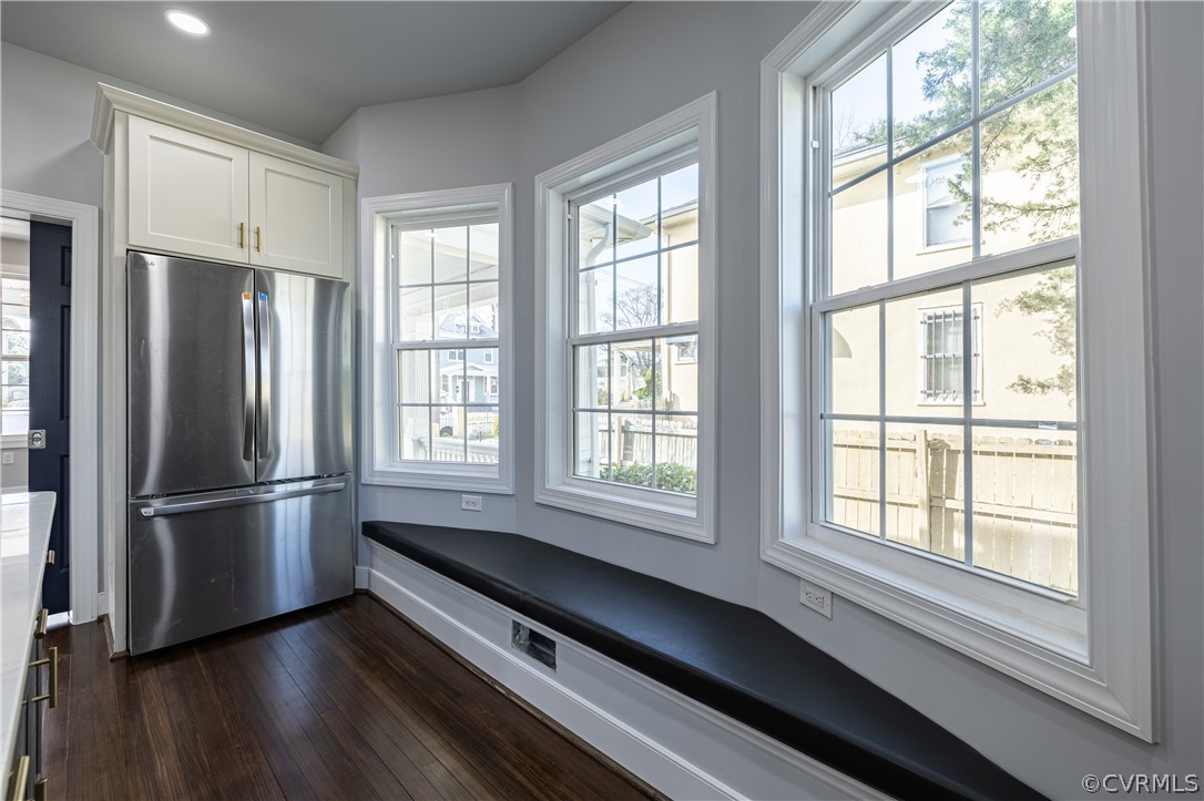 Kitchen with white cabinets, dark hardwood / wood-style floors, and stainless steel fridge