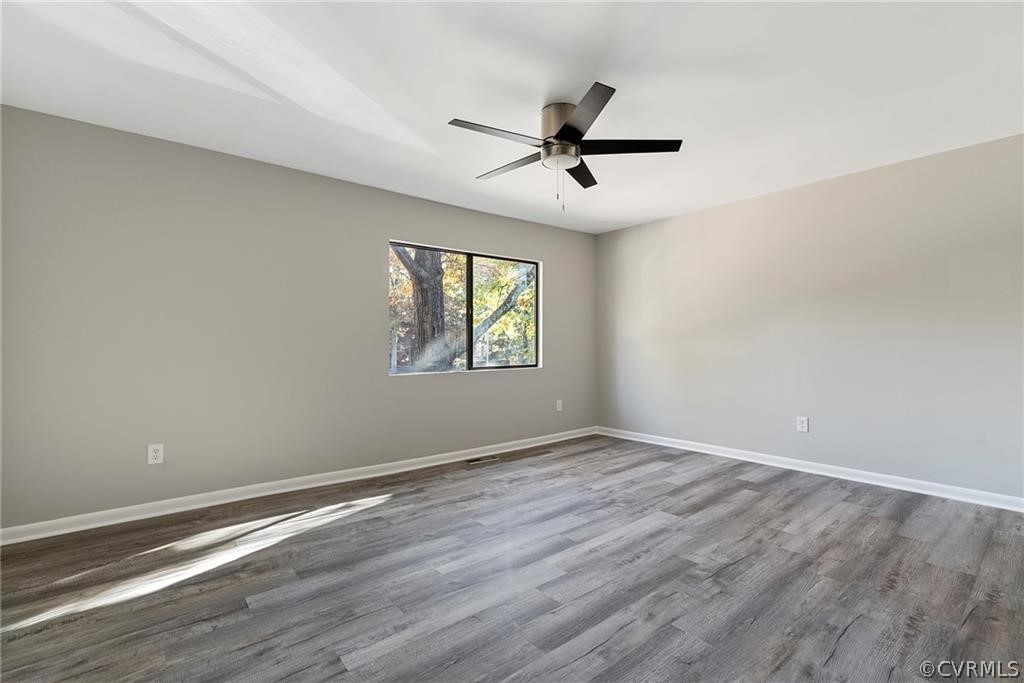 Empty room featuring dark hardwood / wood-style floors and ceiling fan