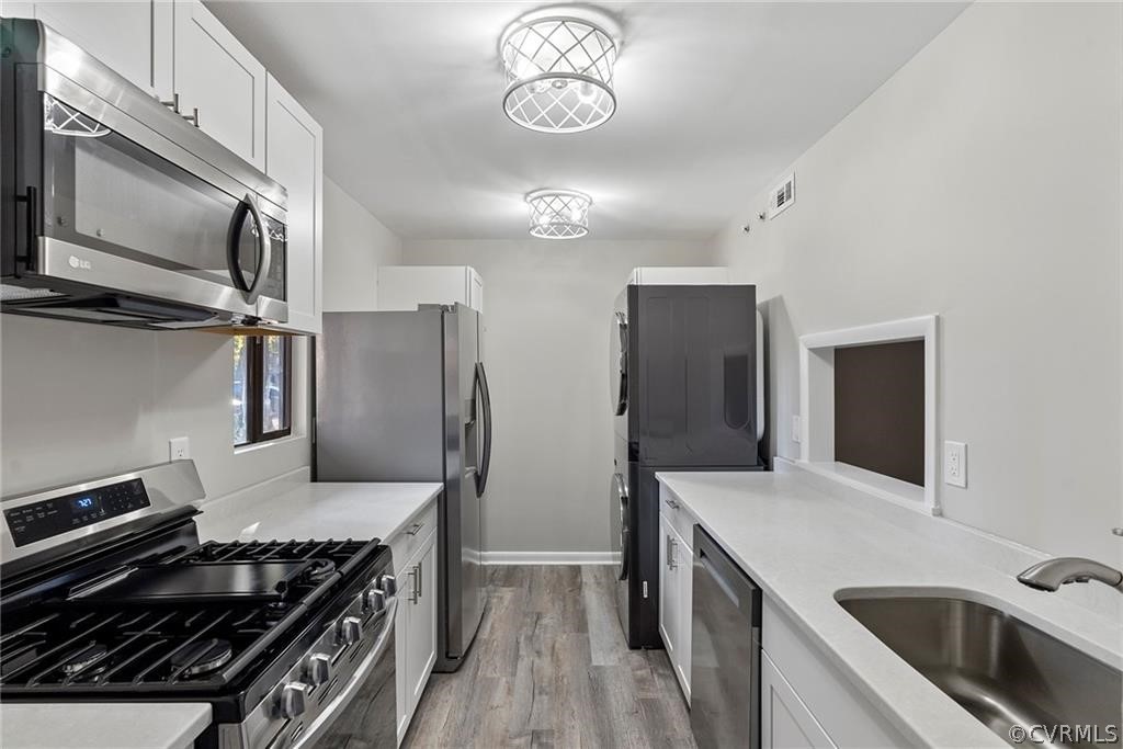 Kitchen featuring white cabinets, light hardwood / wood-style floors, appliances with stainless steel finishes, and sink