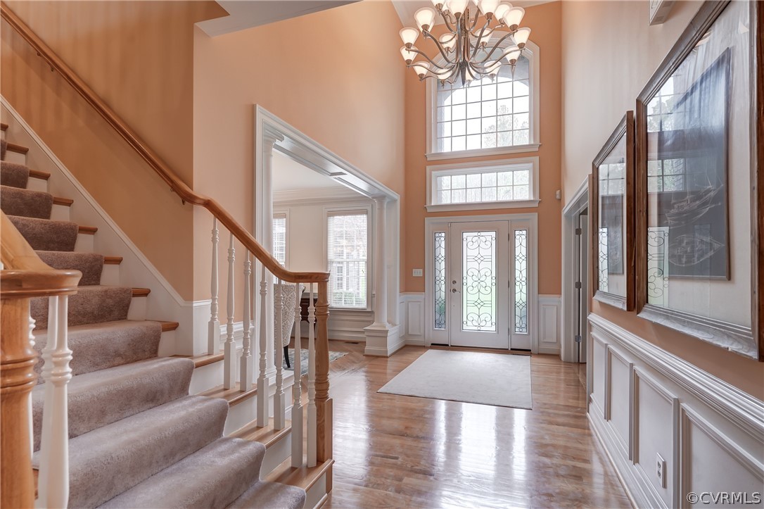 Entryway with an inviting chandelier, a towering ceiling, and light wood-type flooring