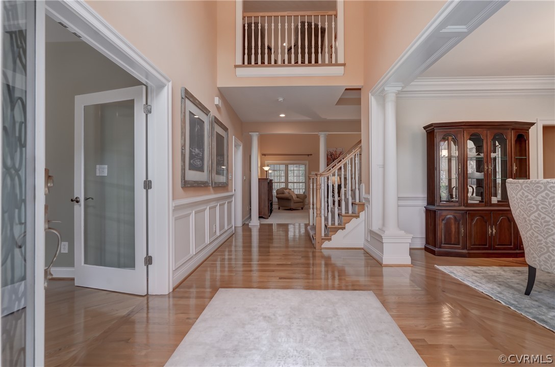 Foyer with ornate columns, crown molding, french doors, and a high ceiling