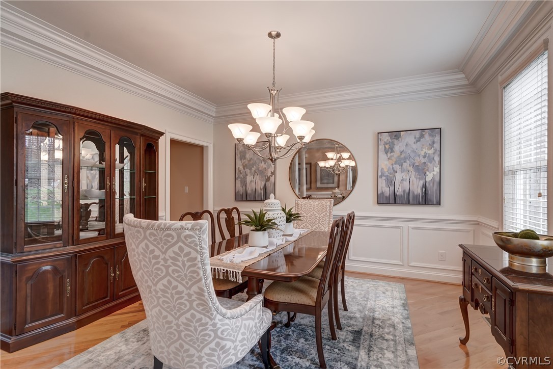 Dining area with a notable chandelier, light hardwood / wood-style flooring, a healthy amount of sunlight, and crown molding