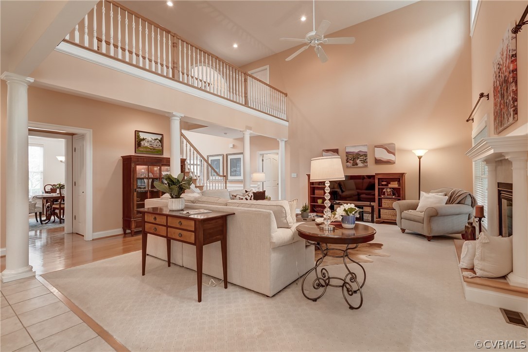Hardwood floors with high vaulted ceiling, ceiling fan, and decorative columns