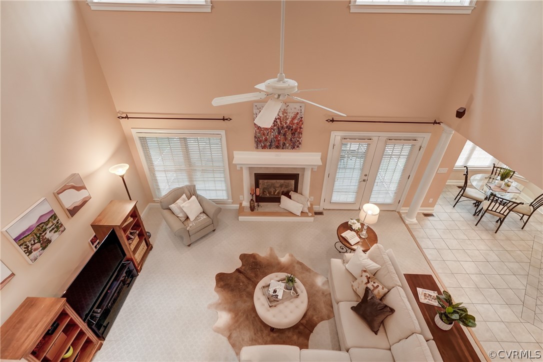 Family room featuring ceiling fan, a healthy amount of sunlight, a high ceiling, and carpet flooring