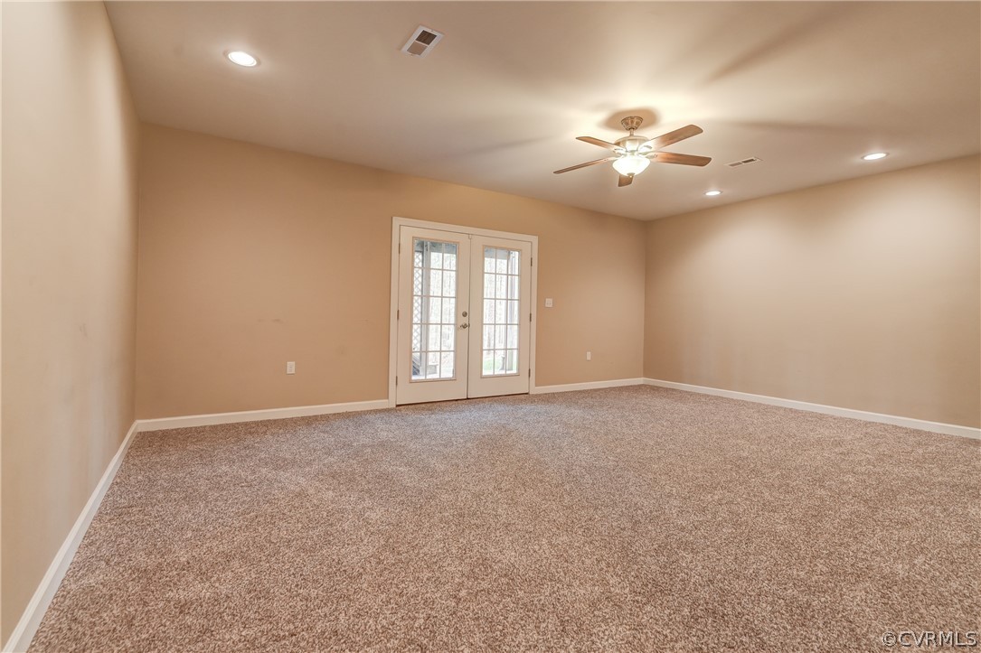 Finished Recreation Room, French doors, light colored carpet, and ceiling fan