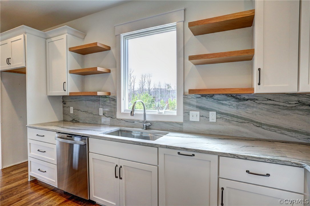 Kitchen featuring stainless steel dishwasher, backsplash, sink, white cabinetry, and dark hardwood / wood-style floors