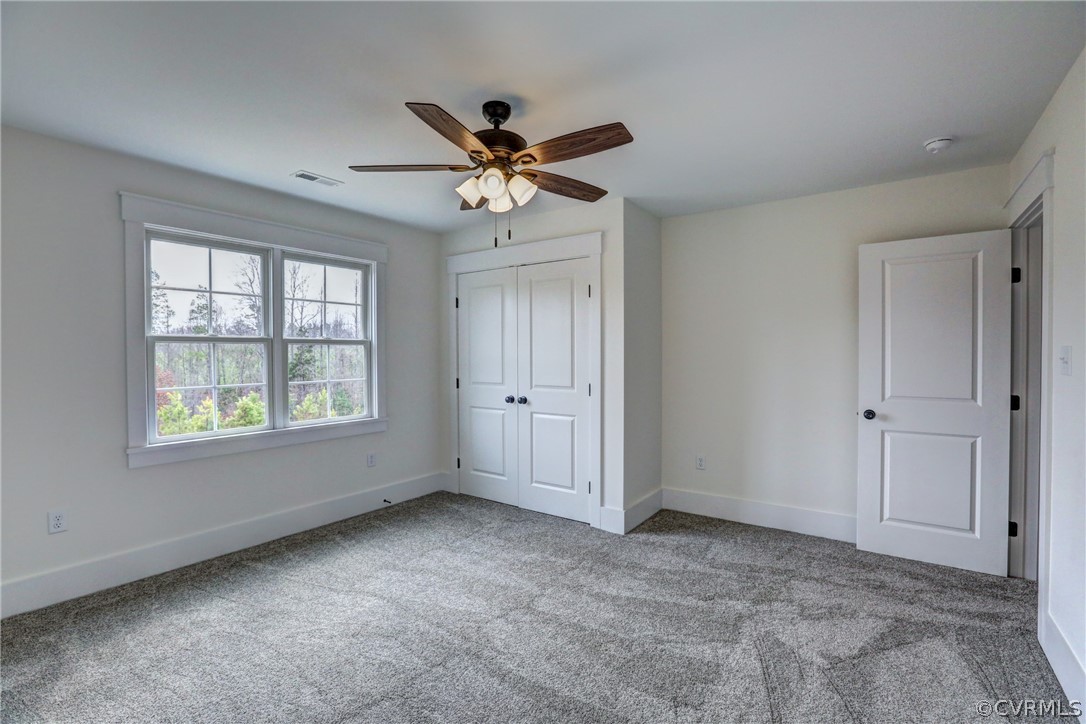 Unfurnished bedroom featuring ceiling fan, light carpet, and a closet