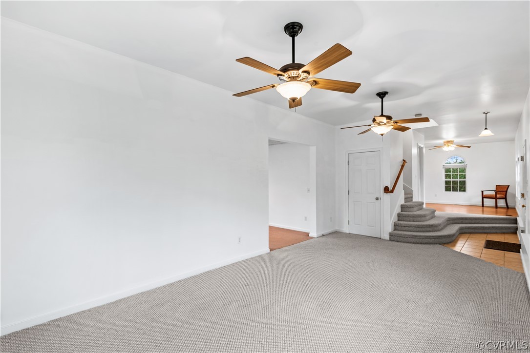 Spacious living room room with ceiling fan and light colored carpet