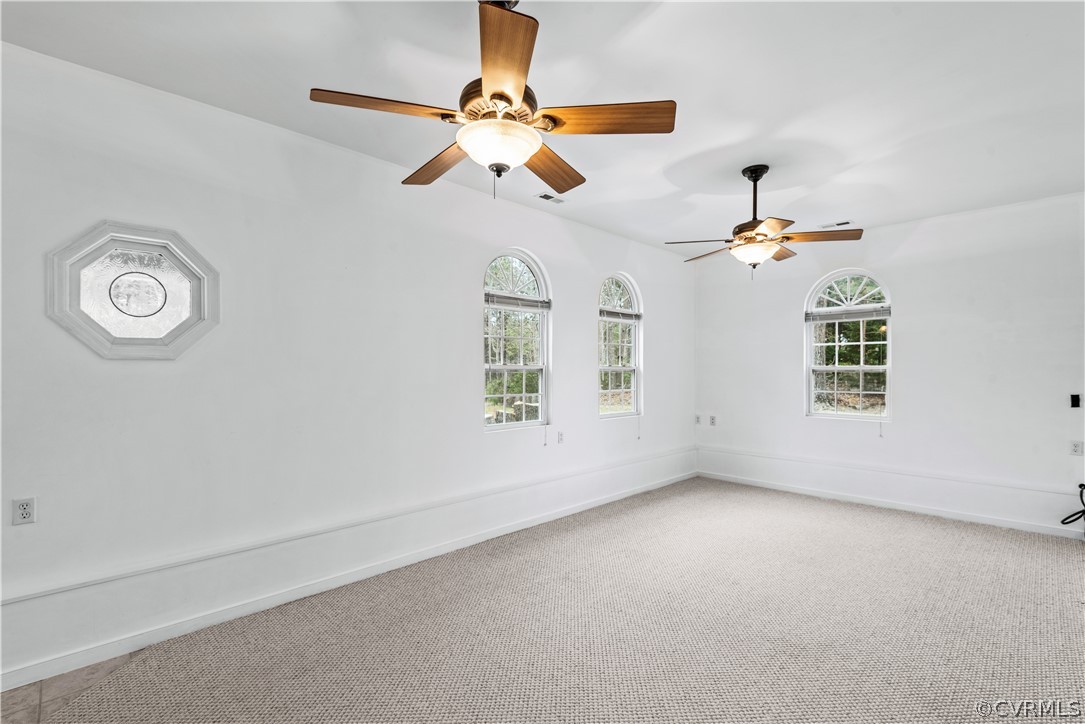 Spare room with ceiling fan, light colored carpet, and plenty of natural light