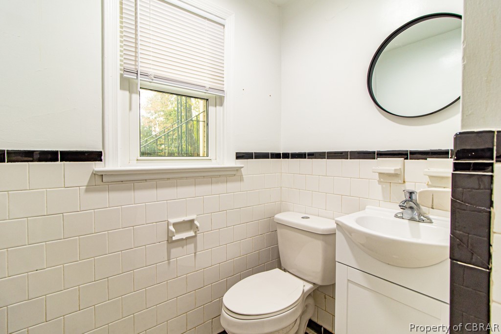 Bathroom with tile walls, vanity, and toilet