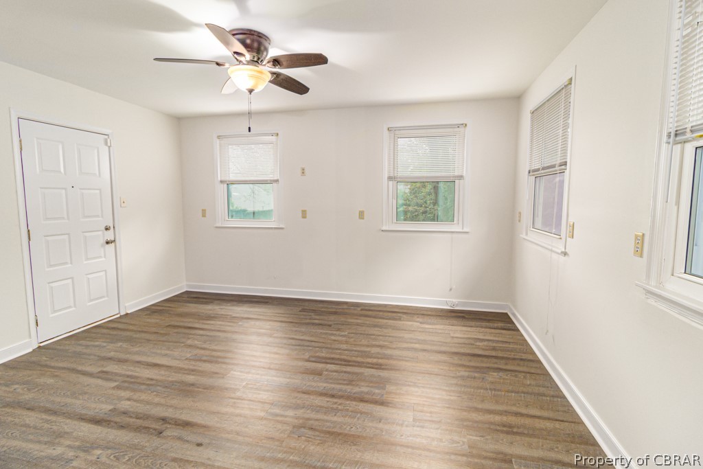 Empty room featuring ceiling fan and dark wood-type flooring