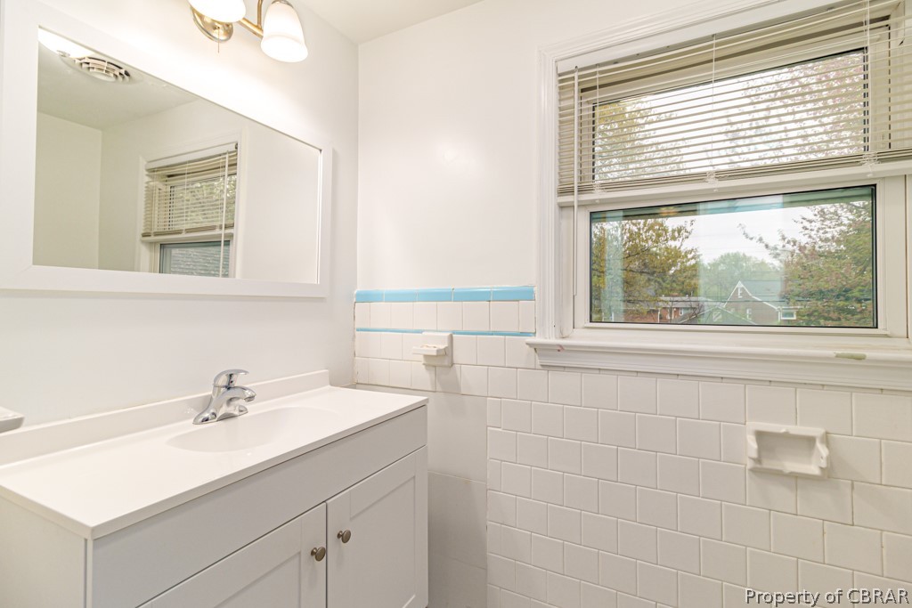 Bathroom featuring vanity and tile walls