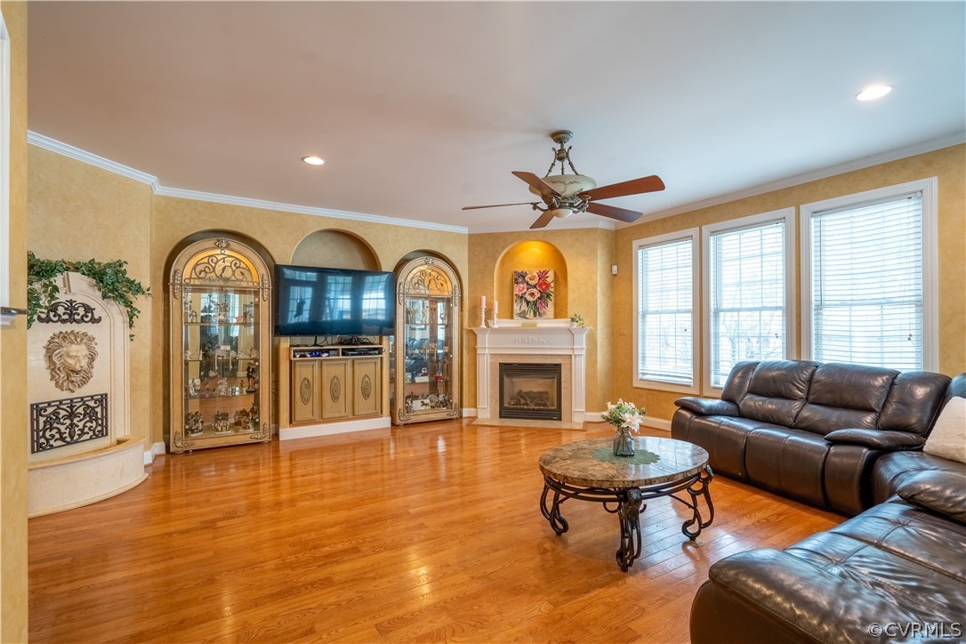 Living room with ceiling fan, molding, and light hardwood / wood-style floors
