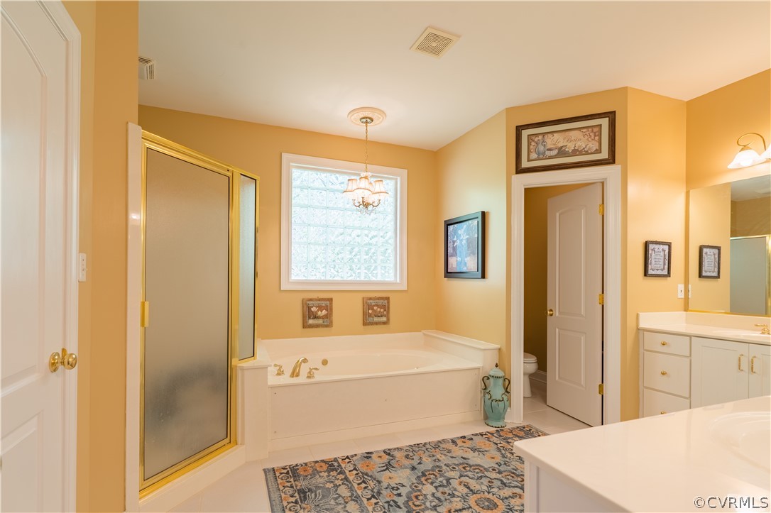 Bathroom featuring plenty of natural light, an inviting chandelier, toilet, and plus walk in shower