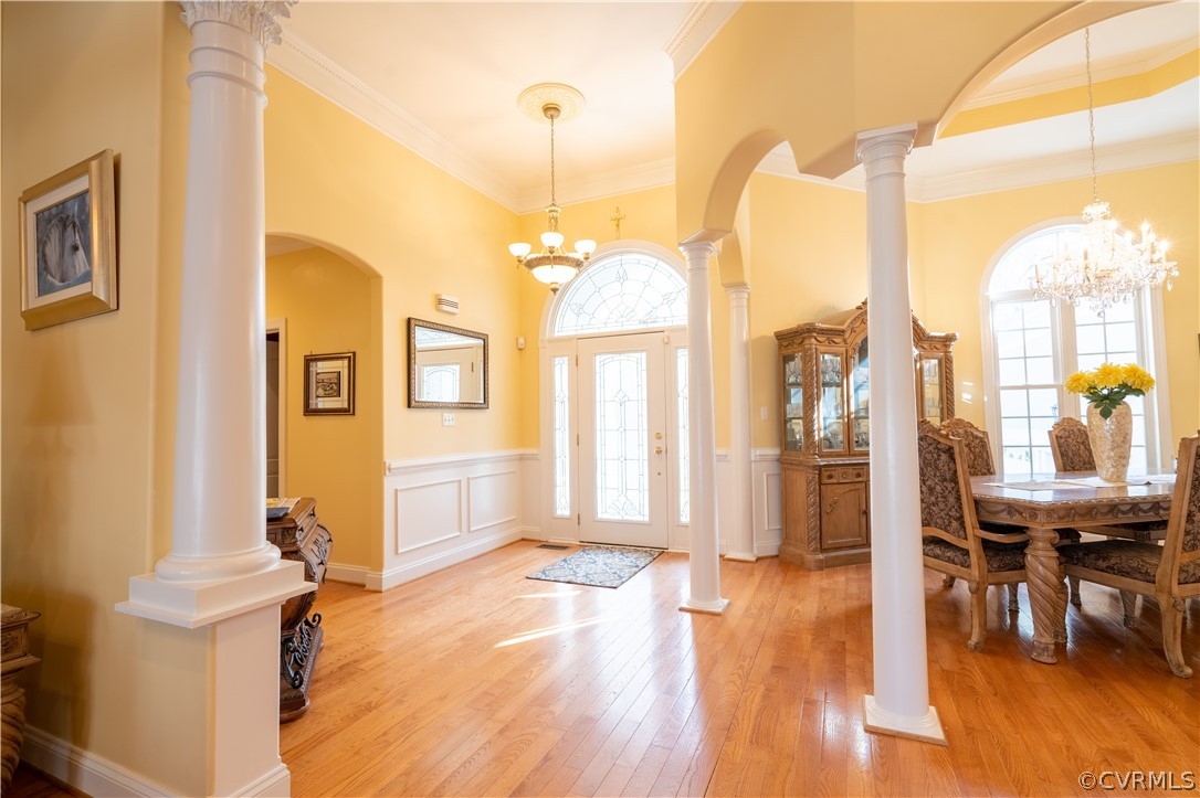 Living room with crown molding, decorative columns, and light hardwood / wood-style floors