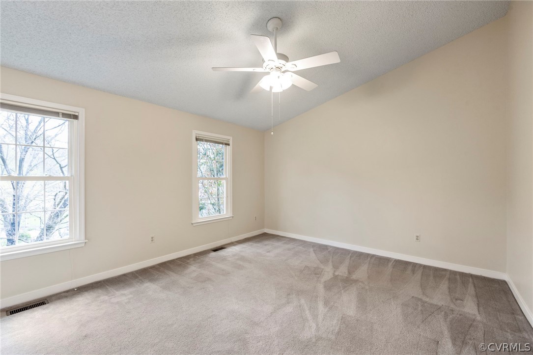 Bedroom with a textured ceiling, carpet, and ceiling fan